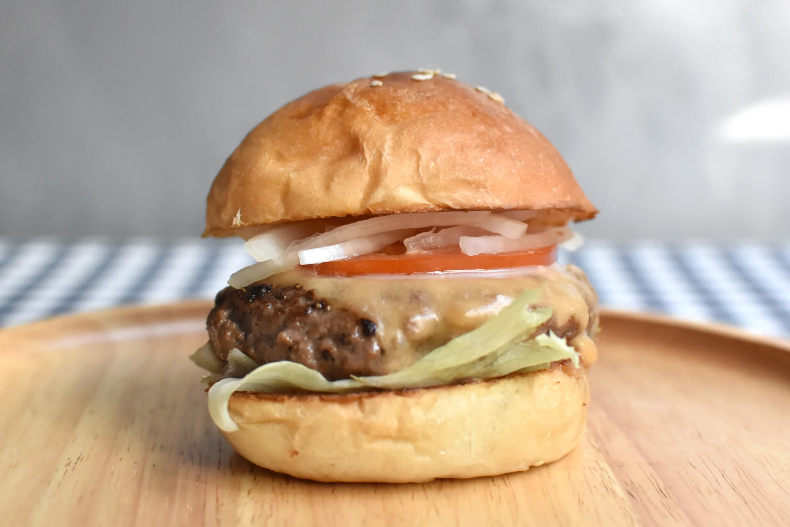 上からオニオン、スライストマト、チーズの溶けたパテ、レタスの順にバンズに挟まれているバーガー